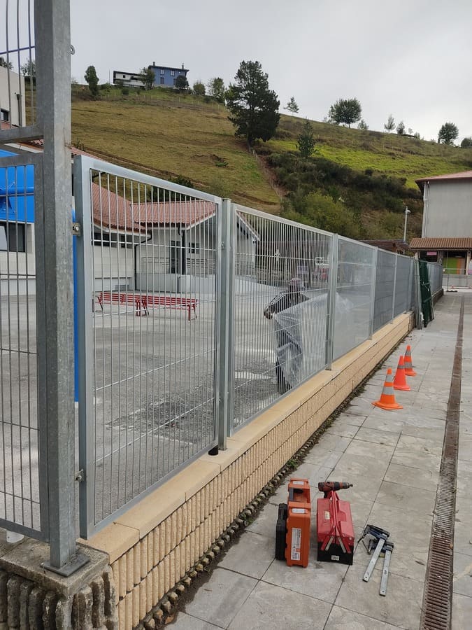 Valla de malla metálica sobre muro de piedra en obra instalada por Kronos SL, Bizkaia