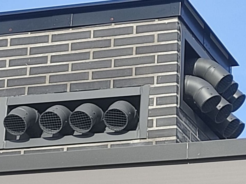 Salidas de ventilación metálicas curvas en fachada de ladrillo por Kronos SL, Bizkaia