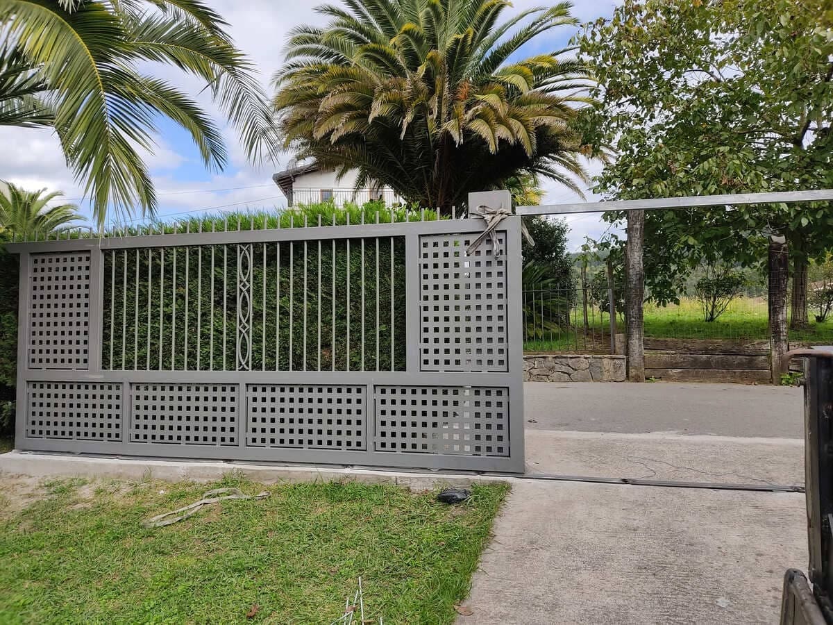 Puerta corredera metálica decorativa en gris con diseño de celosía por Kronos SL