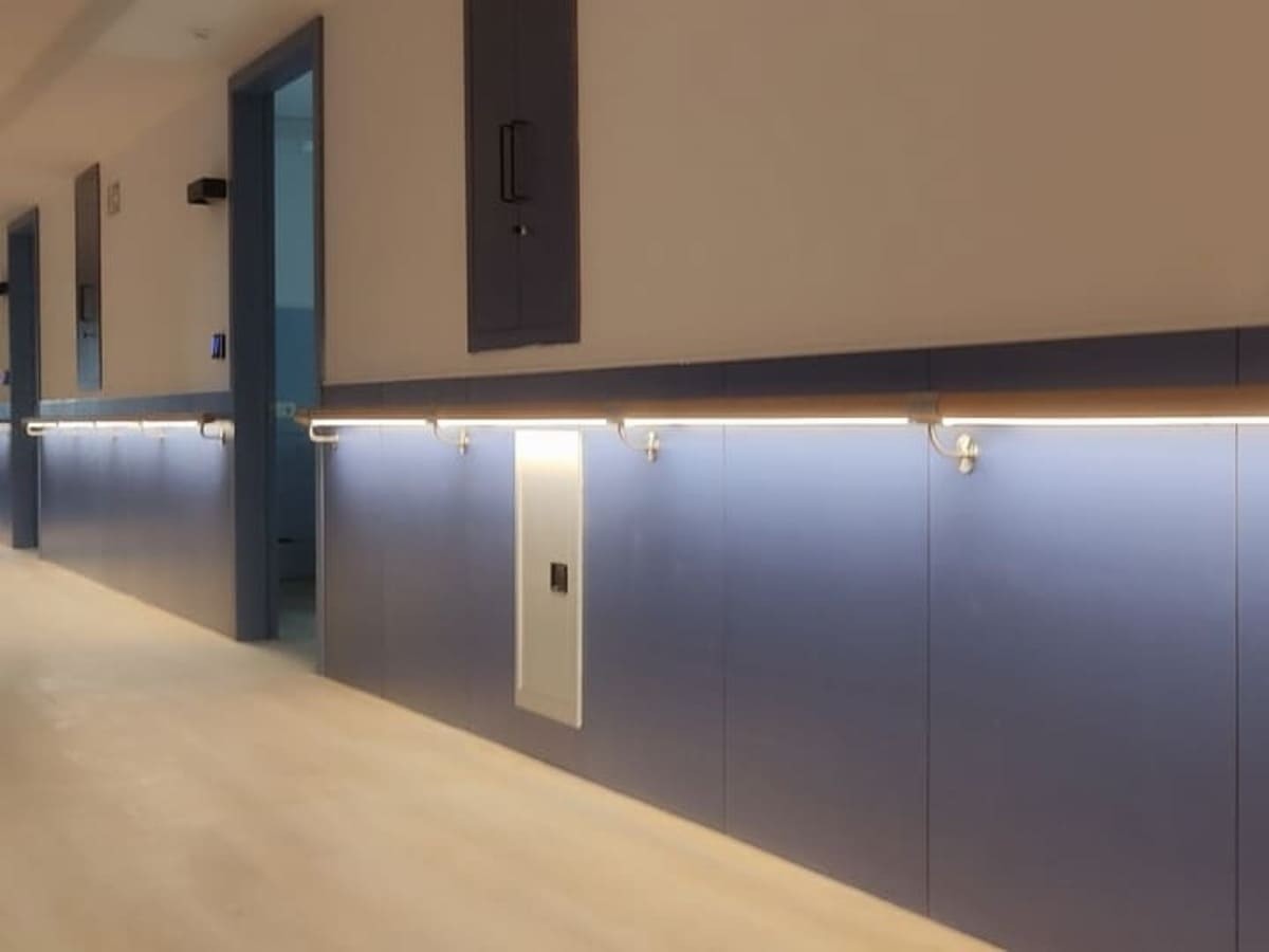 Pasamanos de madera con iluminación LED en pasillo de centro sanitario por Kronos SL